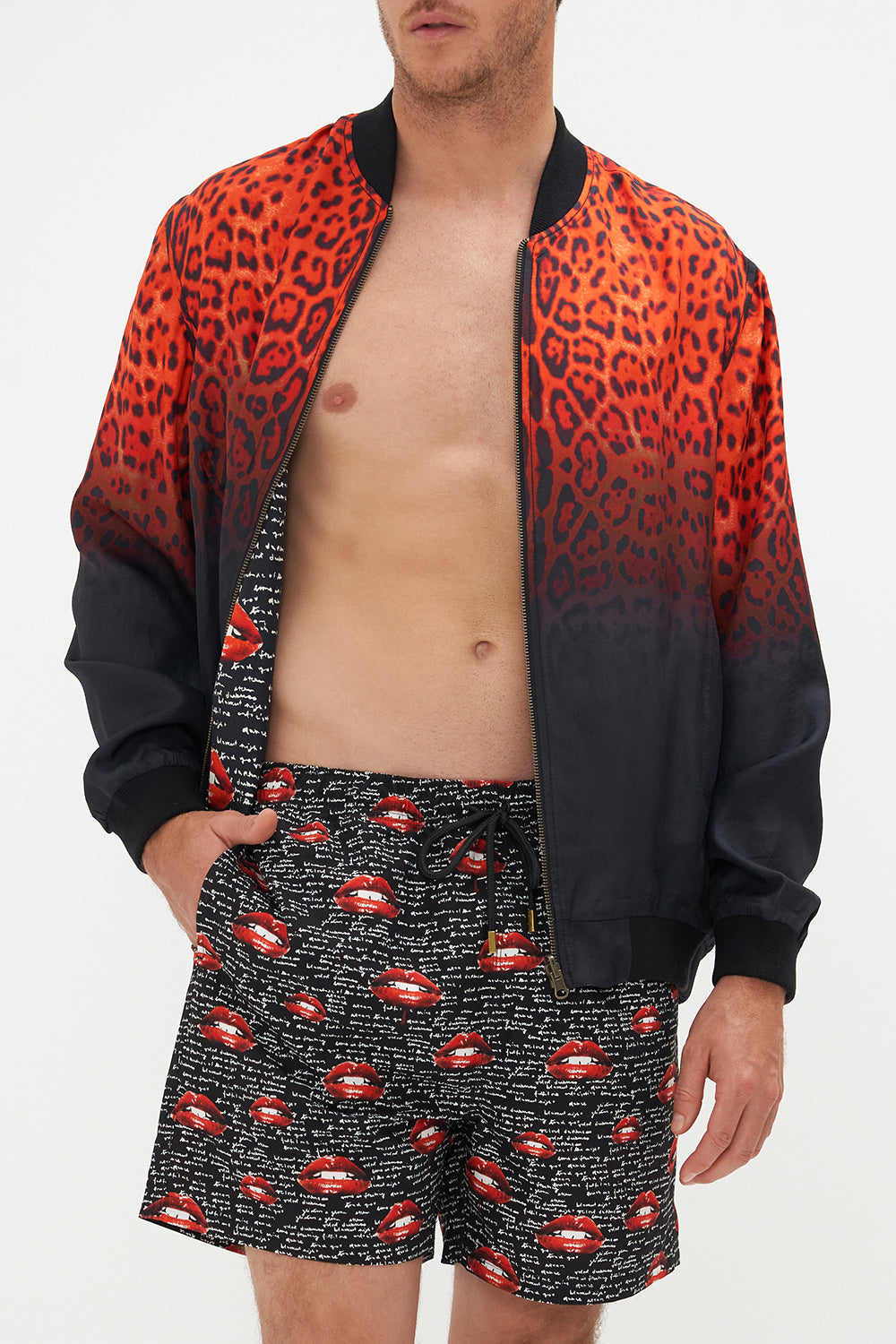 Crop view of model wearing Hotel Franks by CAMILLA mens reversible bomber jacket in black and red Chaos Magic print