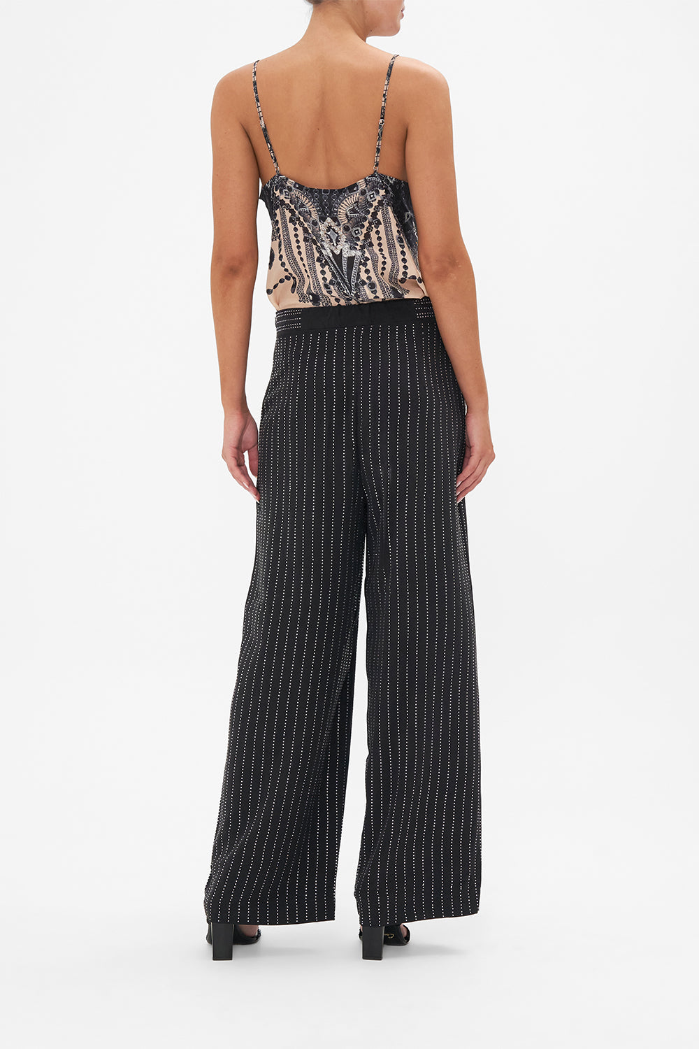 Back view of model wearing CAMILLA floral silk pants in Curtain Call Chaos print