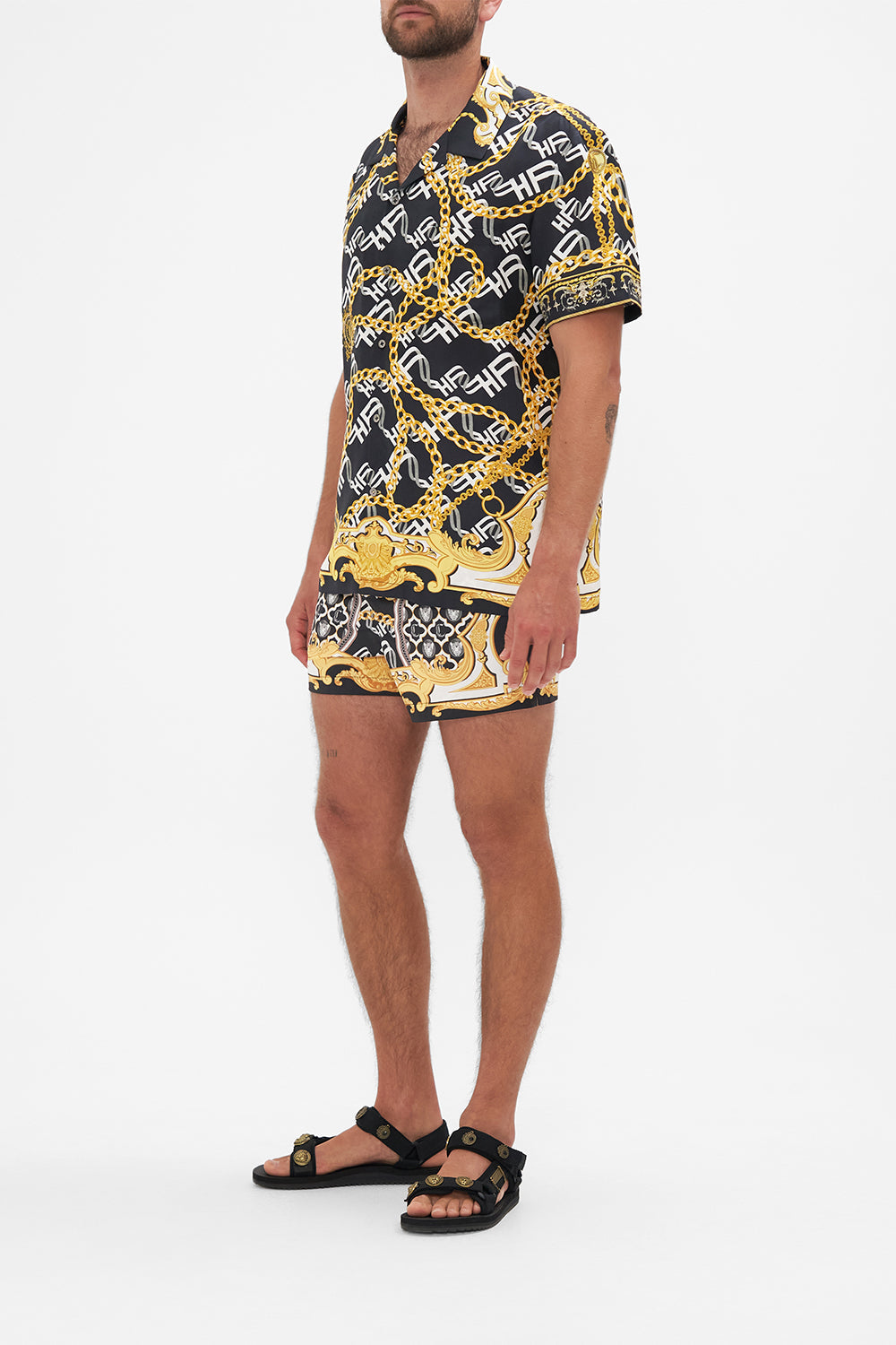 Side view of model wearing Hotel Franks by CAMILLA mens silk short sleeve camp collared shirt in black and gold Tether Me Not print