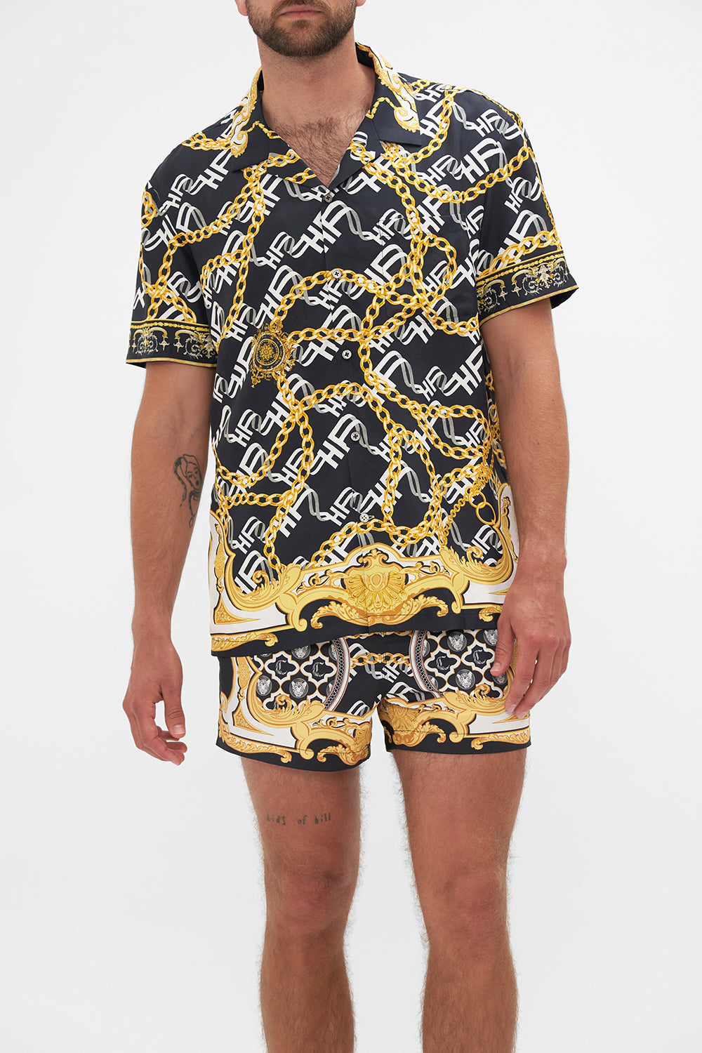 Crop view of model wearing Hotel Franks by CAMILLA mens silk short sleeve camp collared shirt in black and gold Tether Me Not print