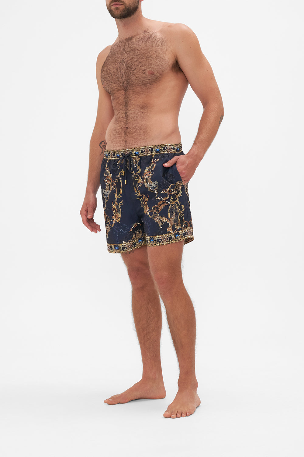 Side view of model wearing Hotel Franks by CAMILLA mens navy boardshorts in Moonlight Melodies print