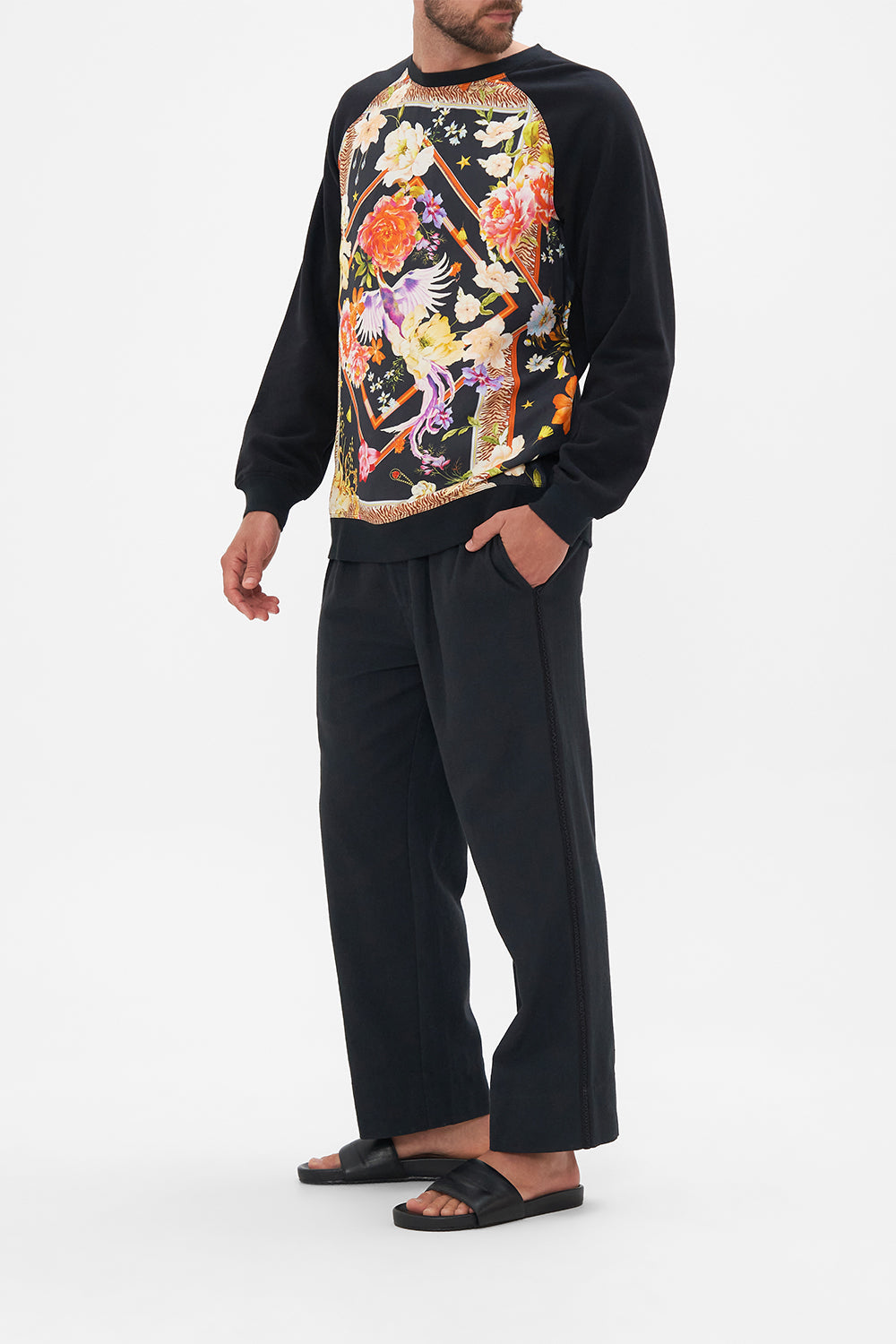 Side view of model wearing Hotel Franks by CAMILLA silk mens black knit jumper in Secret History floral print