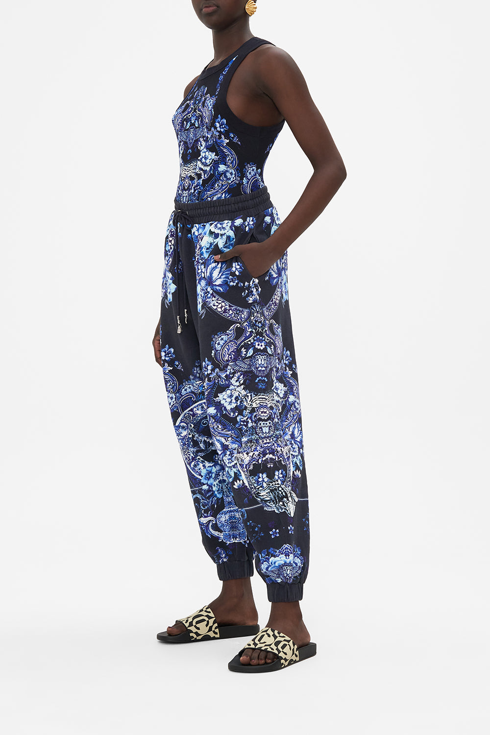 Side view of model wearing CAMILLA designer track pants in Delft Dynasty print 