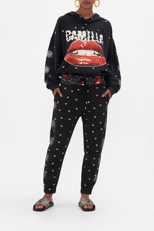 Front view of model wearing CAMILLA black trackpants in Chaos Magic print
