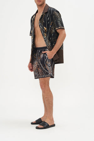 Side view of model wearing Hotel Franks by CAMILLA mens elastic waist boardshorts in Chaos In The Cosmos animal print 