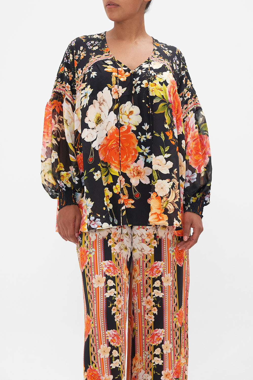 Crop view of model wearing CAMILLA silk blouse in the Secret History print