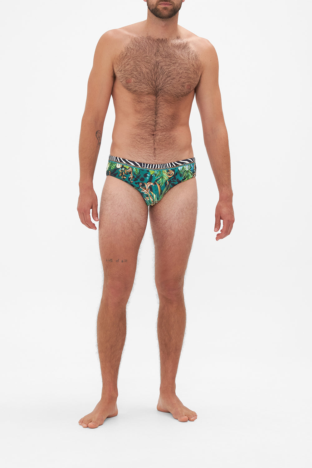 Front view of model wearing Hotel Franks by CAMILLA mens green swim briefs in Sing My Song Print