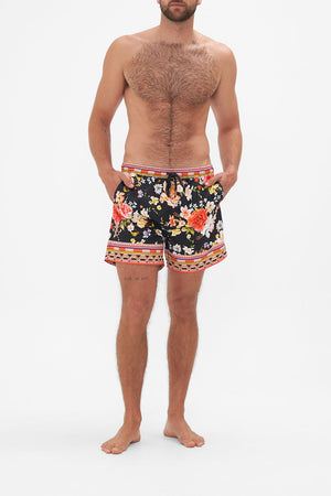 Front view of model wearing Hotel Franks by CAMILLA mens black floral print boardshorts in Secret History print
