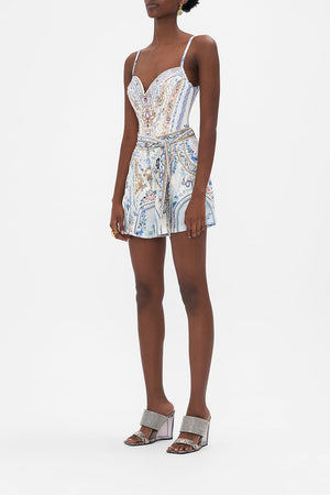 Side view of model wearing CAMILLA designer silk shorts in Season Of The Siren print