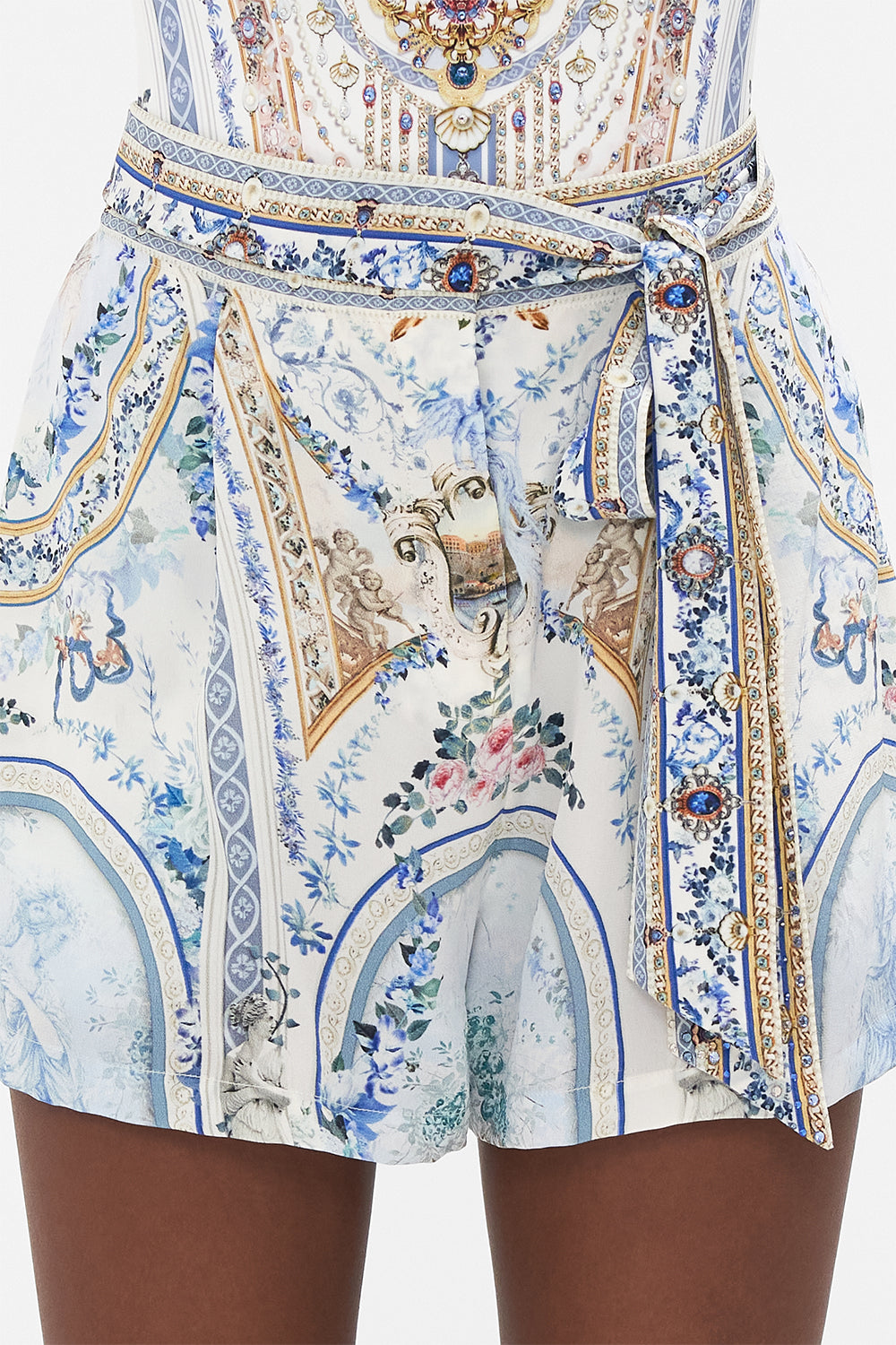 Detail view of model wearing CAMILLA designer silk shorts in Season Of The Siren print