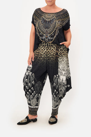 Front view of curvy model wearing CAMILLA  plus size jersey drape pants in Order of Disorder print